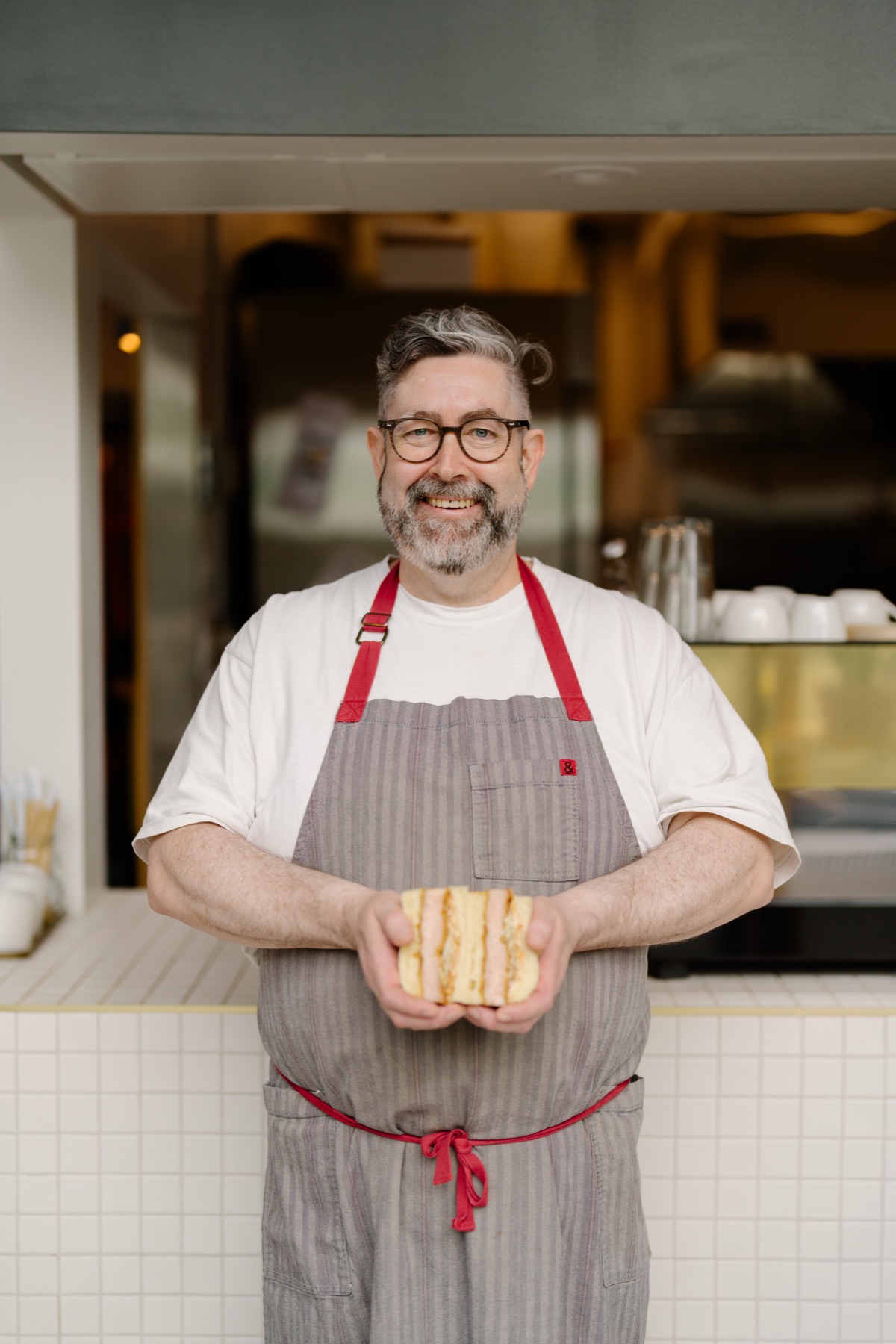 Chael in an apron at District, holding a loaf of shokupan